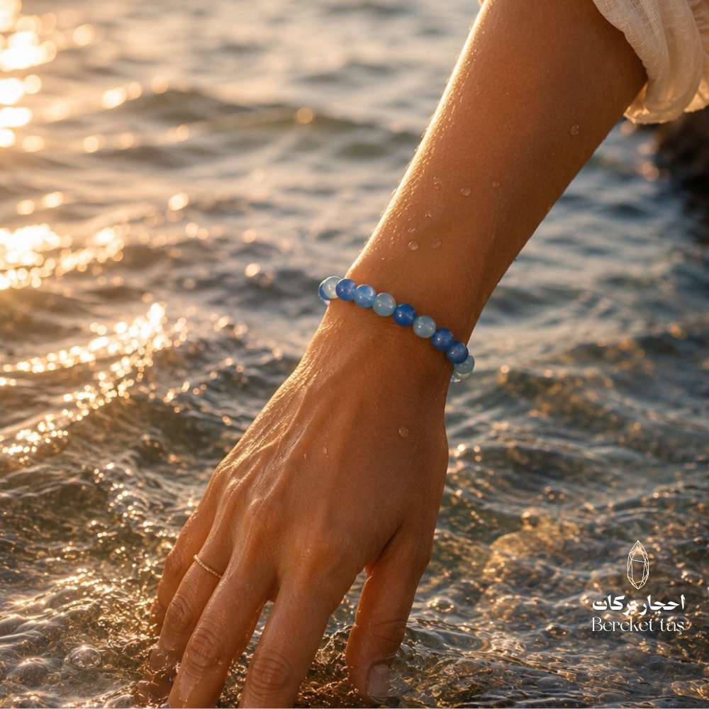 Light sky blue calcite stone bracelet with natural 8 mm beads worn on the wrist in seawater at sunset