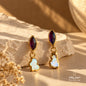 Amethyst and natural Pearl drop earrings with gold-plated metal displayed on a stone surface