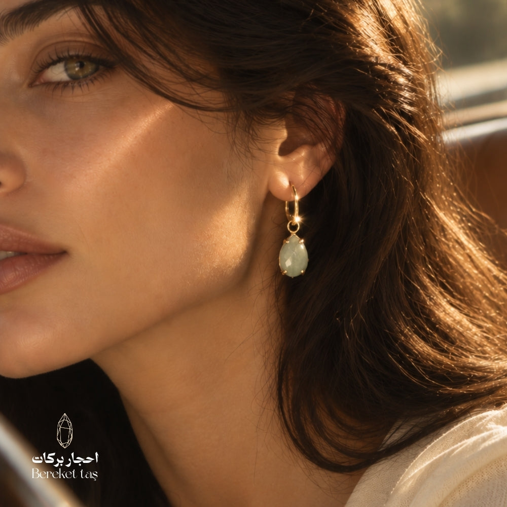 Close-up of a natural Aquamarine teardrop earring with gold-plated metal worn in an elegant look
