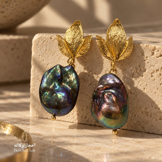 Natural Baroque Pearl earrings with gold-plated copper and detailed gold leaf accents displayed on a stone surface