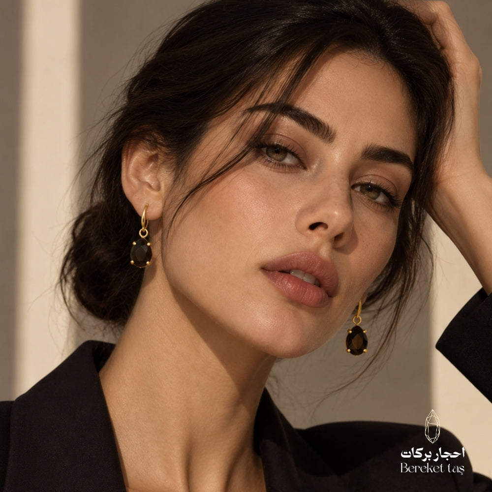 Woman wearing natural Black Onyx drop earrings with gold-plated metal in an elegant portrait