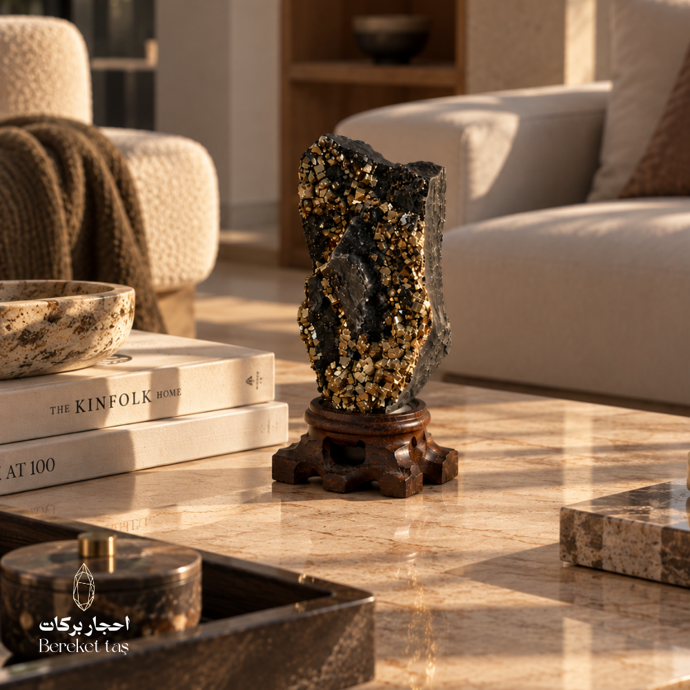 Natural black Shungite with golden Pyrite crystals displayed on a wooden stand in an elegant interior