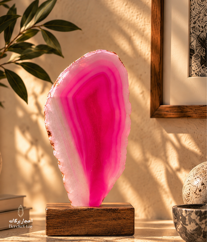 Polished Brazilian pink agate displayed on a wooden base with natural layered bands