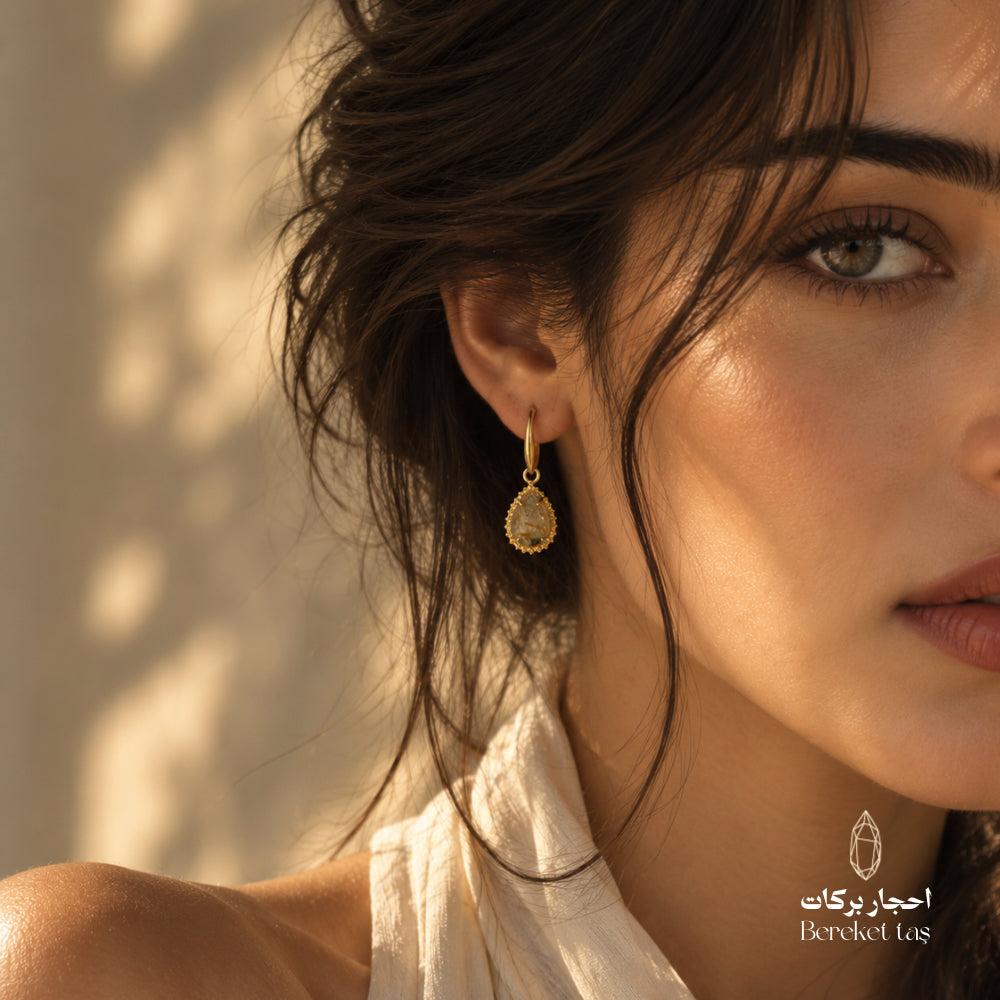 Close-up of a natural Golden Rutilated Quartz drop earring with a gold-plated decorative frame