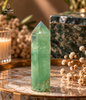 Green fluorite crystal point displayed on a marble table with warm interior styling