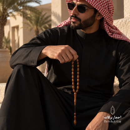Natural Kuka Wood Prayer Beads held by a man in traditional attire, highlighting the polished brown beads and classic design