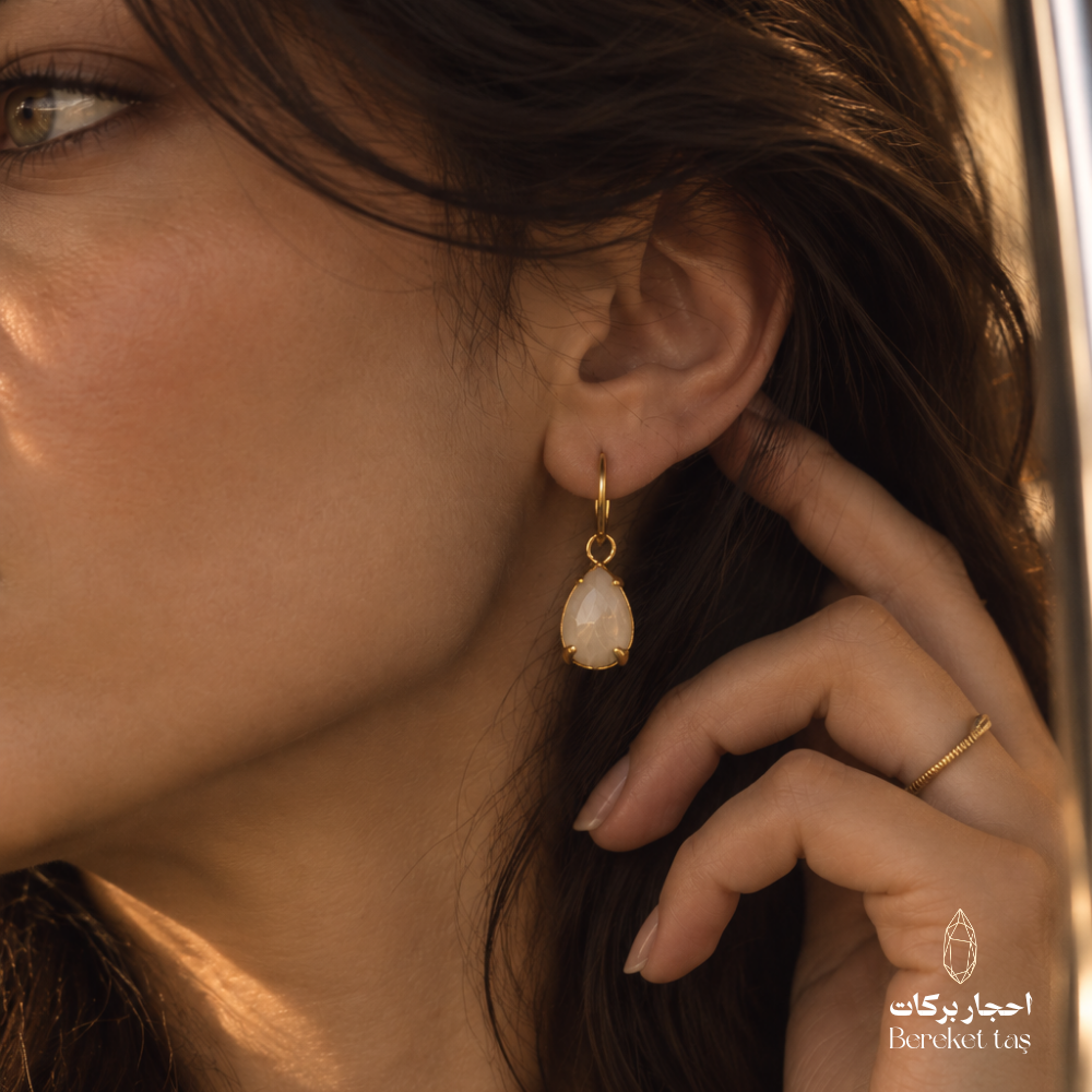 Close-up of a natural Moonstone earring with gold-plated metal worn in an elegant look