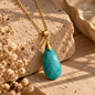 Natural Amazonite pendant necklace with a gold-plated chain displayed on a warm stone surface