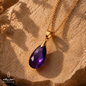Natural Amethyst teardrop pendant necklace with a gold-plated chain displayed on a warm textured stone surface