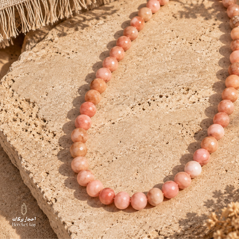 Natural Bambi Opal beaded necklace in soft pink and peach tones displayed on a warm stone surface