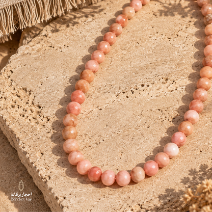 Natural Bambi Opal beaded necklace in soft pink and peach tones displayed on a warm stone surface