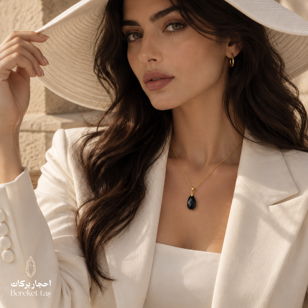 Natural Black Onyx teardrop necklace with a gold-plated chain worn with an elegant white blazer