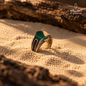 Natural Green Agate men's ring in 925 Sterling Silver displayed on warm desert sand, highlighting the green gemstone and ornate silver detailing.