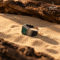 Natural Green Agate men's ring in 925 sterling silver shown from the side on warm sand, highlighting the detailed silver setting