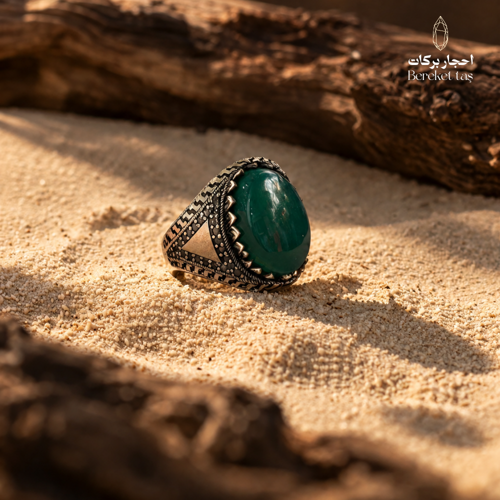 Natural Green Agate men's ring in 925 Sterling Silver displayed on warm sand, highlighting the polished gemstone and ornate silver setting