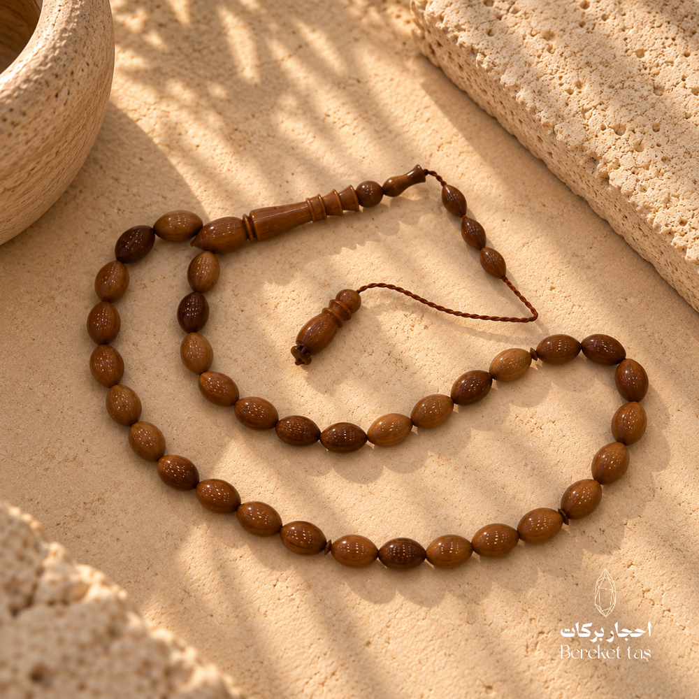 Natural Kuka Prayer Beads with polished oval brown beads arranged on a textured stone surface