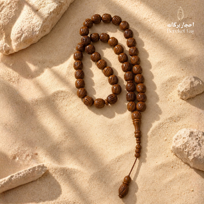 Natural Kuka Prayer Beads arranged on a sandy stone surface, showcasing polished brown wooden beads and classic design