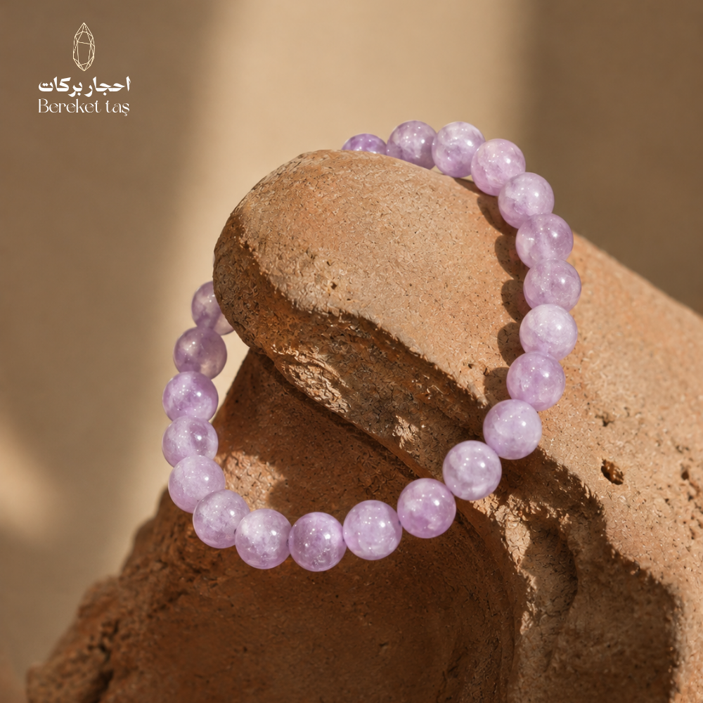 Natural Kunzite stone bracelet with soft pink and purple beads displayed on natural stone