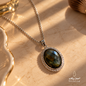 Natural Labradorite Peacock Stone pendant necklace with a silver setting shown in a close-up on a warm stone surface