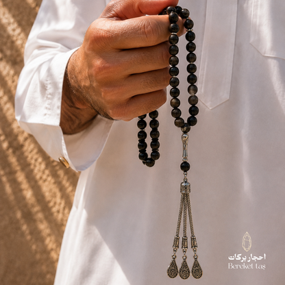 Natural black obsidian stone tasbih close-up held in hand with 10 mm beads by Bereket Taş