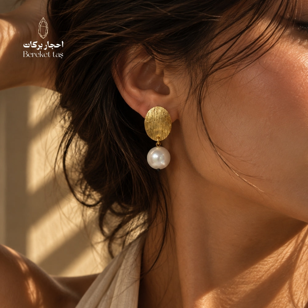 Close-up side view of a natural Pearl earring with textured gold-plated copper detail