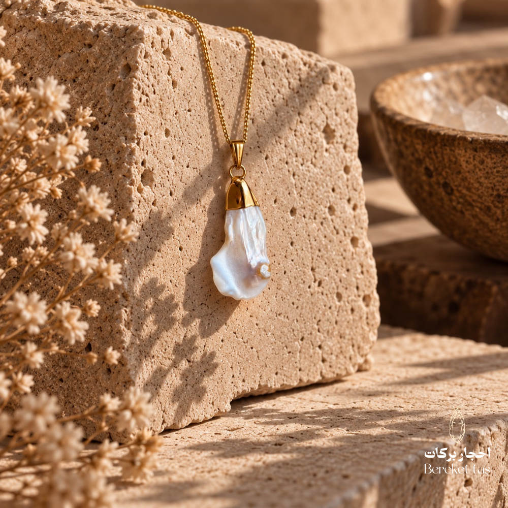 Natural white Pearl pendant necklace with a gold-plated chain displayed on a warm textured stone surface