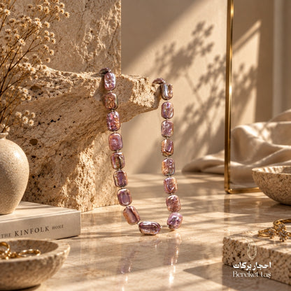 Handmade natural Pearl necklace in pink and light mauve tones displayed on a warm stone surface