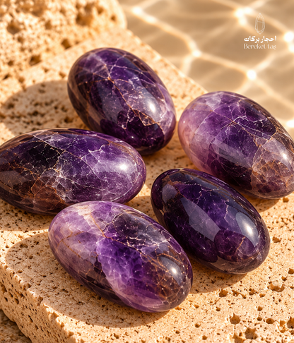 Natural polished Brazilian amethyst stones in varying purple tones displayed on a warm beige stone surface