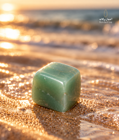 Natural polished green Aventurine stone displayed on wet sand beside the sea at sunset