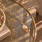 Natural raw Citrine pendant necklace with a silver chain displayed on an elegant glass table