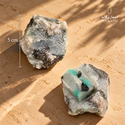 Natural raw Emerald stone from Colombia and Brazil displayed on a warm beige surface with its length measurement shown