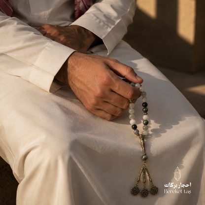 Natural rutilated quartz tasbih prayer beads held by a man wearing a white thobe