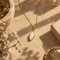 Natural shell stone pendant necklace with a gold-plated chain displayed on a warm stone surface