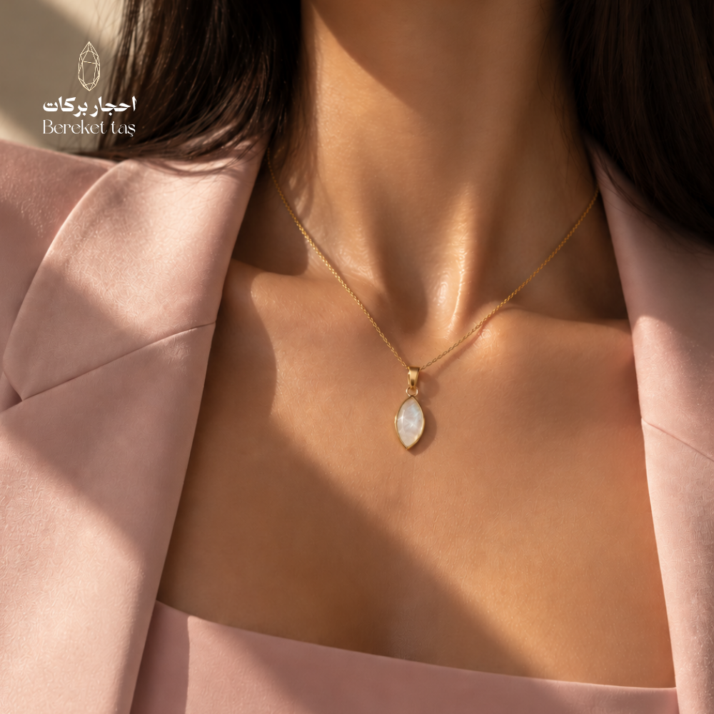 Close-up of a natural shell stone pendant necklace with a gold-plated chain worn with a pink outfit