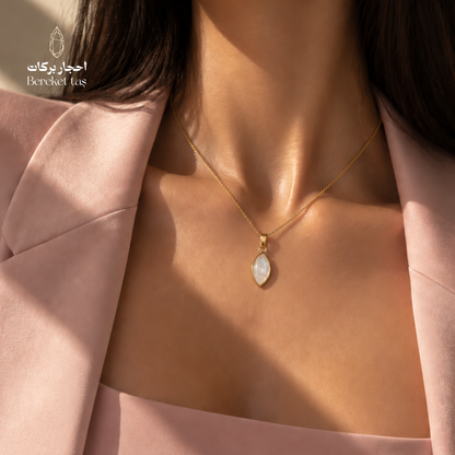 Close-up of a natural shell stone pendant necklace with a gold-plated chain worn with a pink outfit