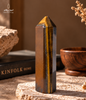 Natural South African Tiger’s Eye stone with golden chatoyancy displayed upright on a travertine surface