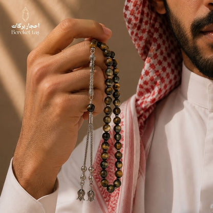 Natural Tiger Eye mesbaha held with traditional Arabian attire, featuring honey brown and dark green beads