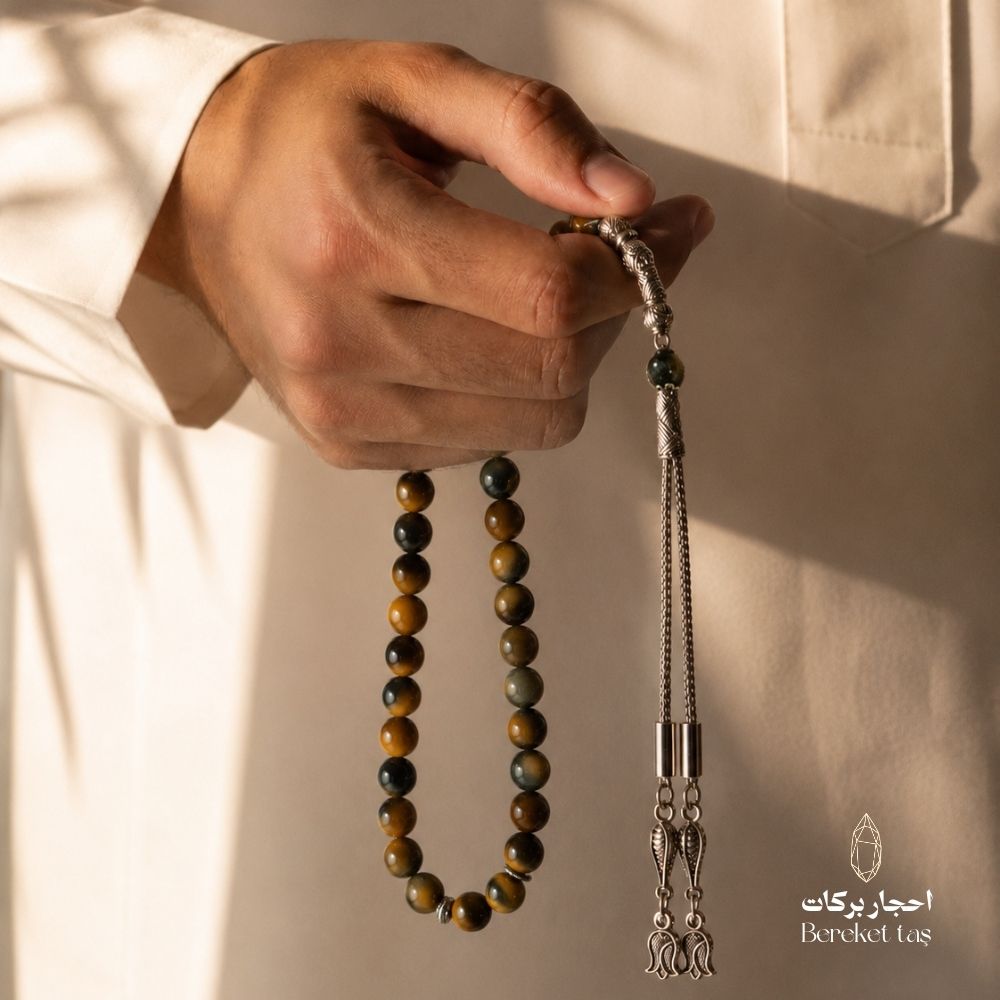 Natural Tiger Eye mesbaha held with an Arabian thobe, featuring honey brown and dark green beads