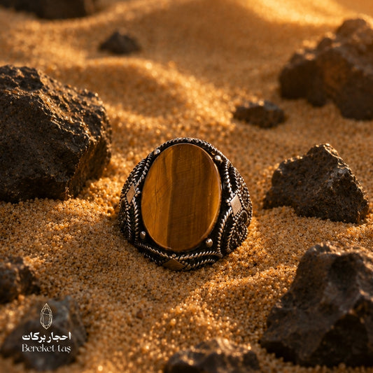 Natural Tiger Eye ring with honey brown stone and 925 silver, photographed on sand with natural rocks
