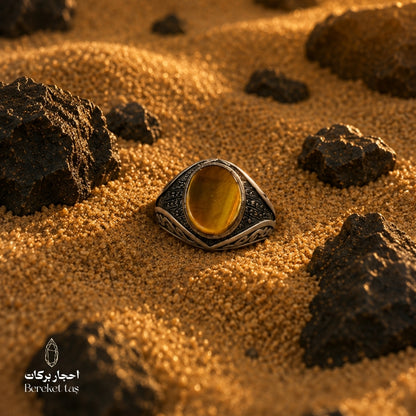 Natural Tiger Eye ring with honey brown stone and 925 silver, photographed on sand with natural rocks