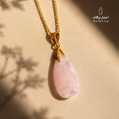 Natural pink Quartz pendant necklace with a gold-plated chain on a warm beige background