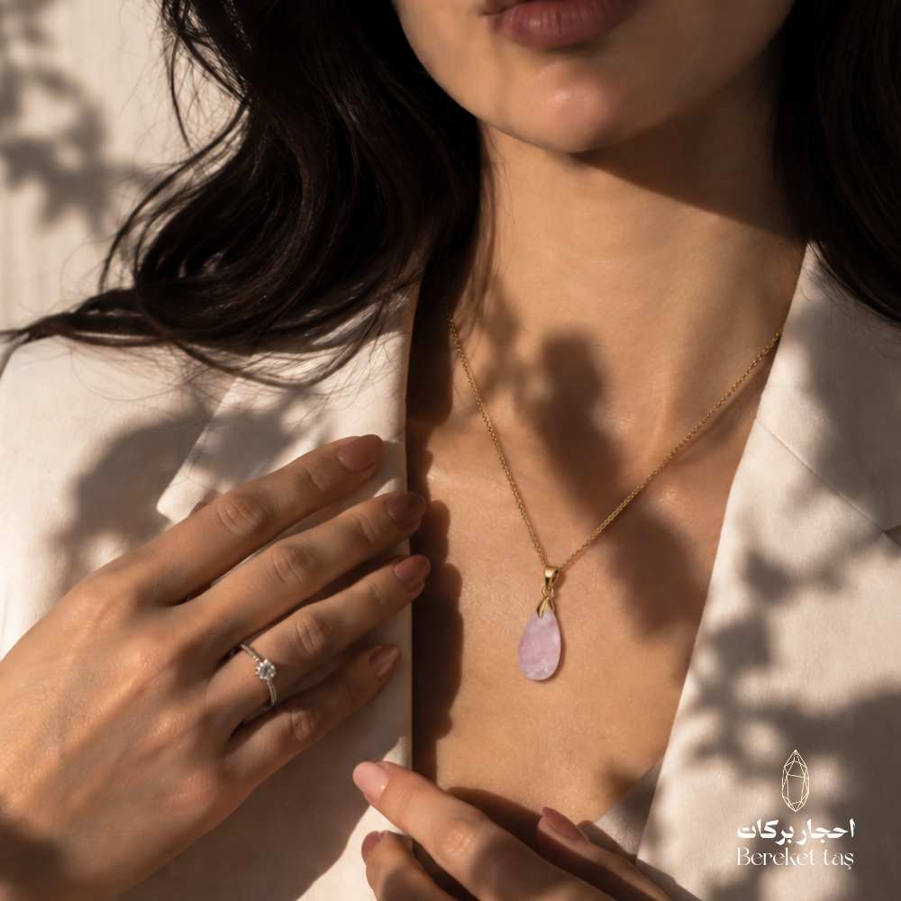 Close-up of a natural pink Quartz pendant necklace with a gold-plated chain worn with a white outfit