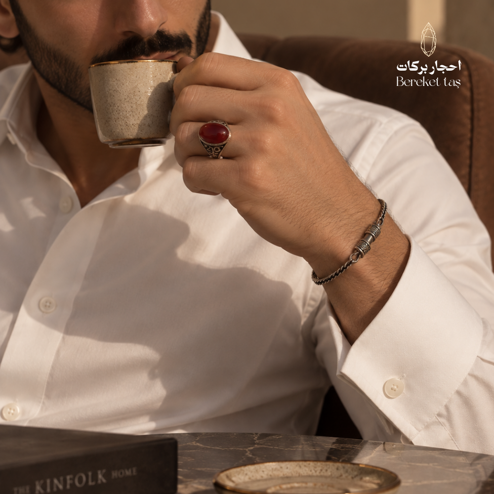 Man wearing a natural Red Agate ring in 925 Sterling Silver while holding a coffee cup, styled in a white traditional outfit.