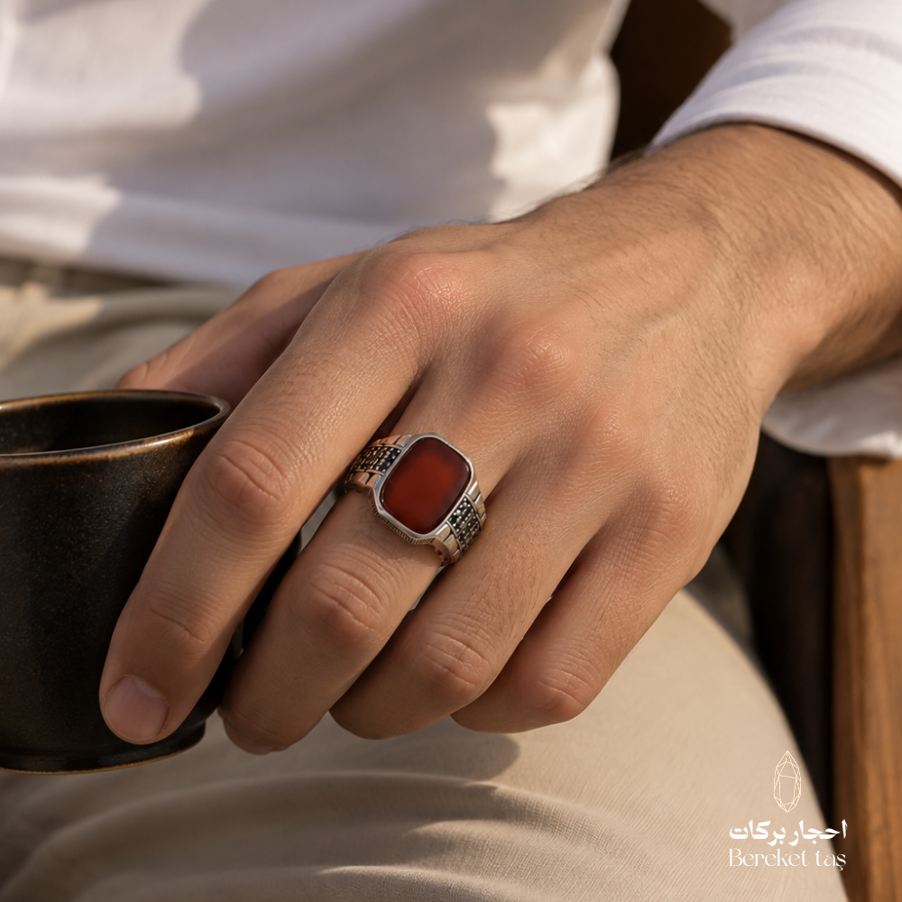 Natural Red Agate men's ring in 925 Sterling Silver worn on a man's hand beside a coffee cup, highlighting the rectangular gemstone and detailed silver setting.