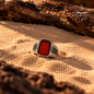 Natural Red Agate men's ring in 925 Sterling Silver displayed on warm sand, showcasing the deep red gemstone and geometric silver detailing.