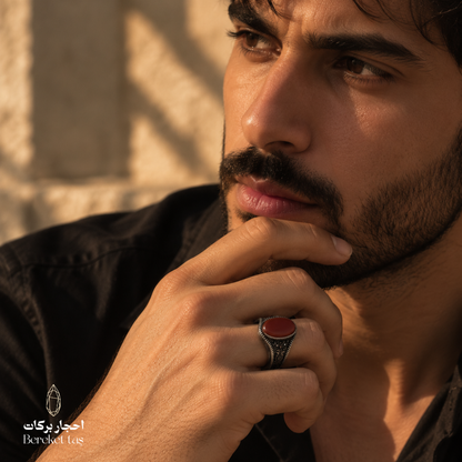 Man wearing a natural Red Agate ring in 925 Sterling Silver, shown in a close-up portrait that highlights the deep red gemstone and ornate silver setting.