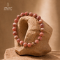 Pink Rhodochrosite stone bracelet with 8 mm beads displayed on a natural stone sculpture