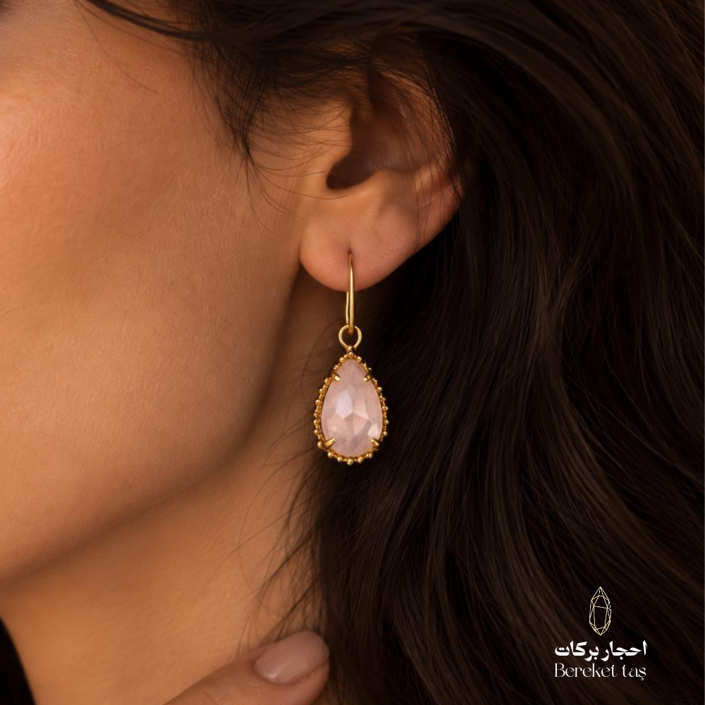 Close-up of a natural Rose Quartz teardrop earring with a delicate gold-plated frame